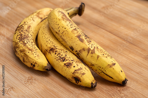 Three ripe bananas on a wooden cutting board