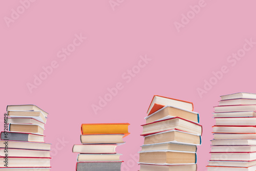 Composition with hardback books on wooden deck table and pink background. Books stacking. Back to school. Copy Space. Education background.
