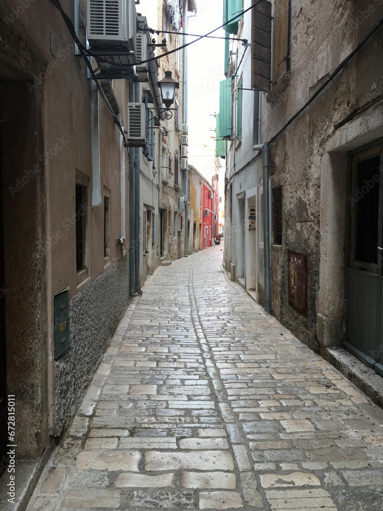 Obraz premium Picturesque alleyway between two buildings in a town or city, leading into the unknown
