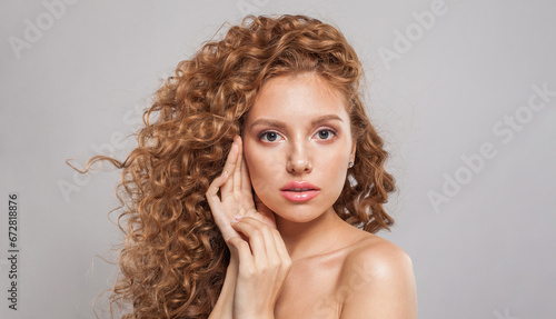 Glamorous stylish young female model with curly long brown hairstyle on white background. Woman with wavy hair