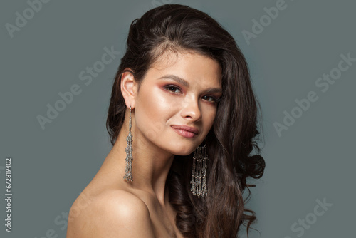 Cute female face. Brunette woman with healthy dark hair wearing long jewelry earring, fashion beauty portrait