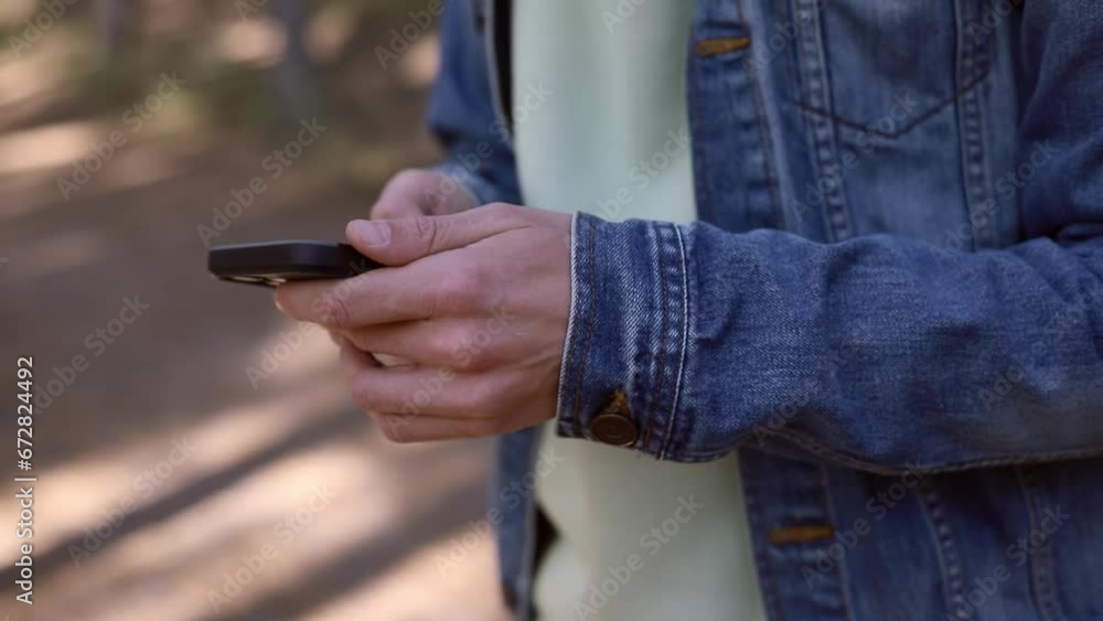 Close up mobile phone in the hands of a male traveler walking through the forest. Social networks Navigator and messenger. Use your mobile phone for a walk in the woods Close up mobile phone in the hands of a male traveler walking through the forest. Social networks Navigator and messenger. Use your mobile phone for a walk in the woods