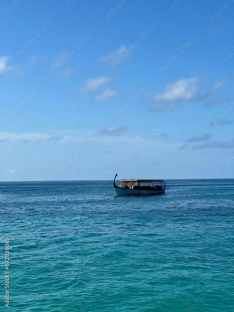 Vertical shot of a boat on bright blue water under a clear sky