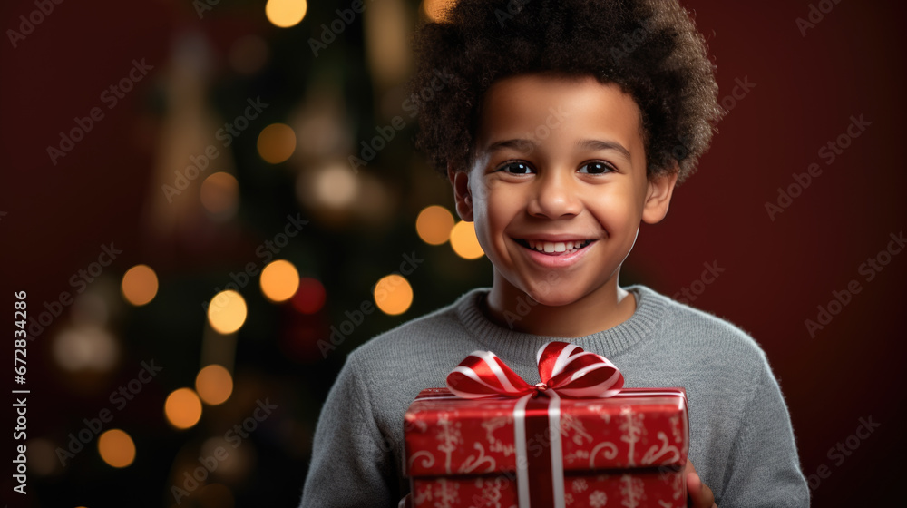 A delighted boy with a beaming smile holds a Christmas present , surrounded by the festive glow of tree lights and ornaments. A delighted boy with a beaming smile holds a Christmas present , surrounded by the festive glow of tree lights and ornaments.