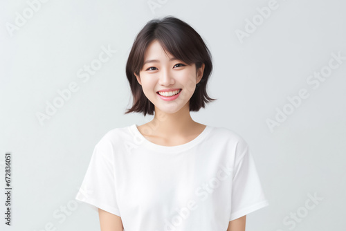 An Asian girl with captivating big eyes, a short bobtail hairstyle, and a subtle smile exudes cuteness and innocence against a semi desaturated gray backdrop. Generative AI. photo