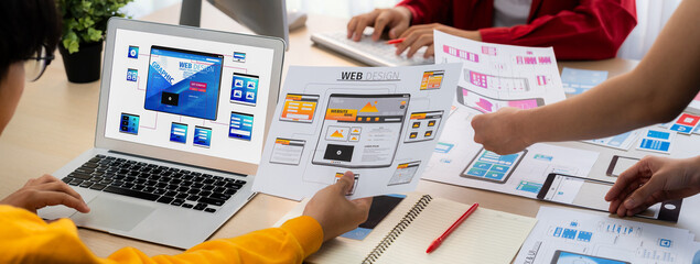 Panorama banner of startup UX developer or company employee design user interface or UI prototype for mobile application or website software with software display on laptop monitor in office. Synergic
