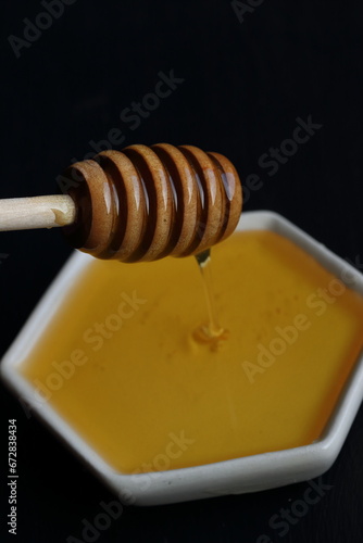 Fresh Honey with wooden honey spoon on a black background