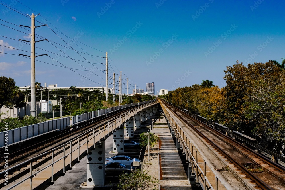 Closeup  of a railway surrounded by lush green trees under the blue sky on a sunny day