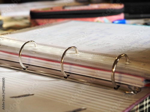 Open ring binder with handwritten papers on a desk
