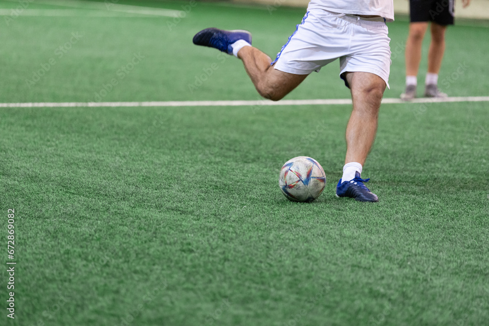 Football Futsal ball and man player legs on artificial grass field indoors. Football Futsal ball and man player legs on artificial grass field indoors.