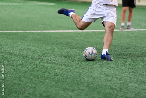 Football Futsal ball and man player legs on artificial grass field indoors. © zphoto83