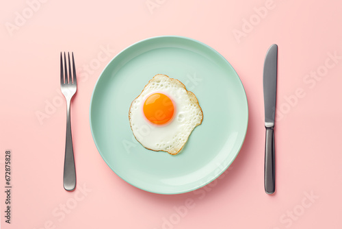 Sunny-side up or fried egg in a mint plate with fork and knife on pastel pink background. Minimalistic breakfast concept. Creative healthy breakfast idea. AI generated content.