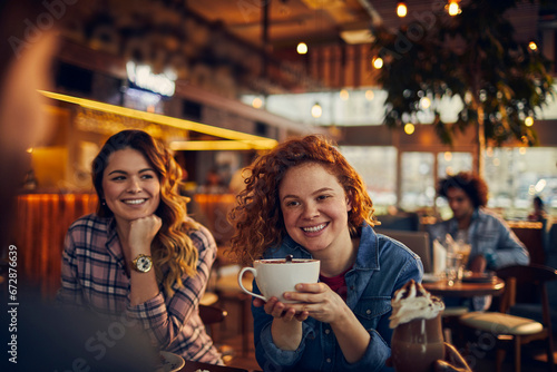 Young woman holding a mug in cafe with friends photo