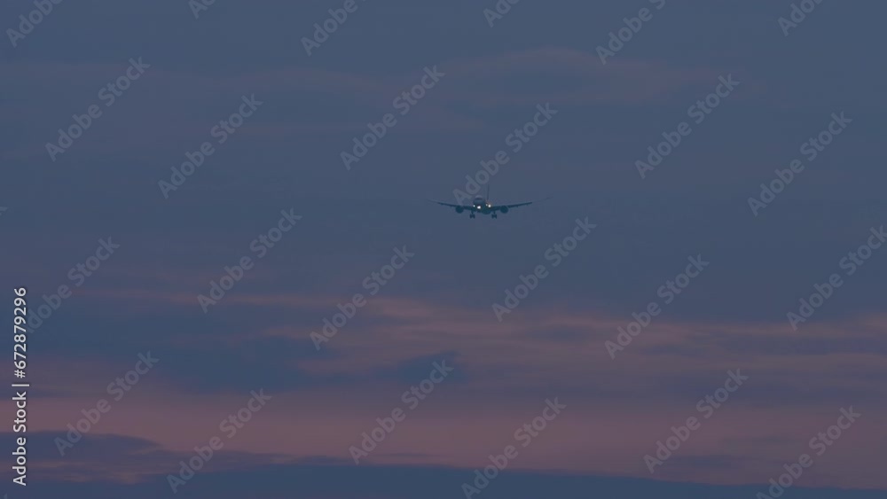 Long shot of a jet passenger plane approaching landing in a gloomy sky. Sunset or dawn, airplane in the sky. Airliner descent, arrival. Travel concept Long shot of a jet passenger plane approaching landing in a gloomy sky. Sunset or dawn, airplane in the sky. Airliner descent, arrival. Travel concept