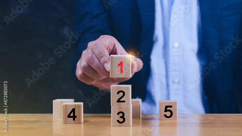 Task priority and management concept, The order of priority in any activity, Set work priority, arrange to do list. Hand arranging Wooden cube blocks with number first, second, third, four, five. photo