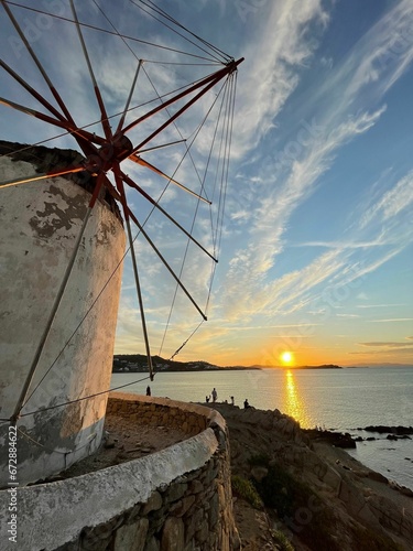 Idyllic scene of a row of white-washed windmills against a sunset sky in Mykonos, Greece