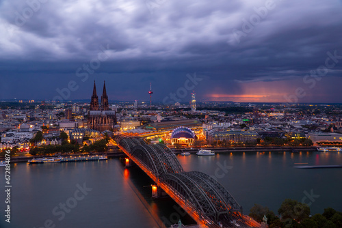 Dramatic storm clouds over Cologne Cathedral and Hohenzollern Bridge in the sunset