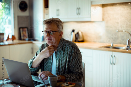Mature man holding throat working on laptop at home photo