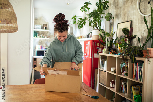 Young woman unpacking box in the kitchen photo