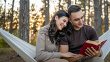 Man and woman young adult couple in nature hold and read book in love