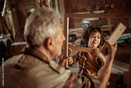 Little boy learning in grandfather carpenter shop
