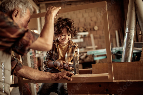 Little boy learning in grandfather carpenter shop