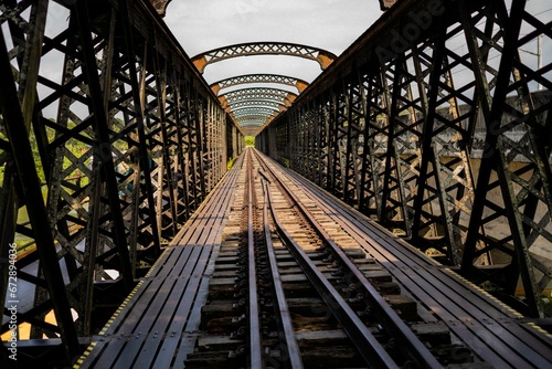 Fototapeta Naklejka Na Ścianę i Meble -  Elevated railway bridge with an old-fashioned design, spanning a wide river