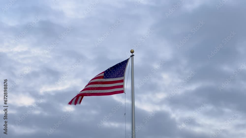 Flag of the USA fluttering in the wind with blue sky in the background Flag of the USA fluttering in the wind with blue sky in the background