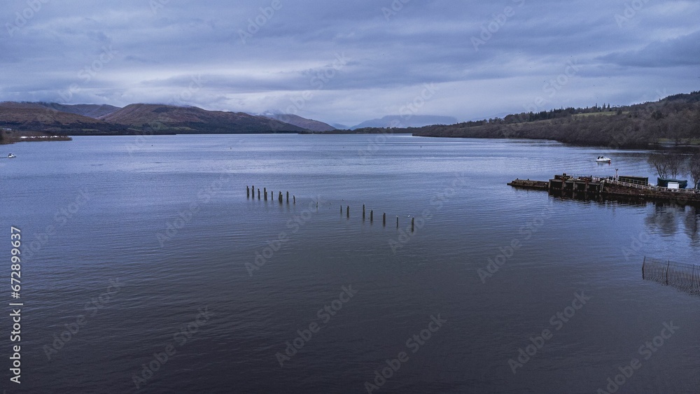 Aerial of a pier on a cloudy day in Loch Lomond, Scotland