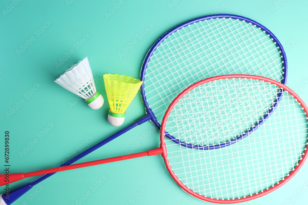 badminton rackets and shuttlecocks in a green background. 