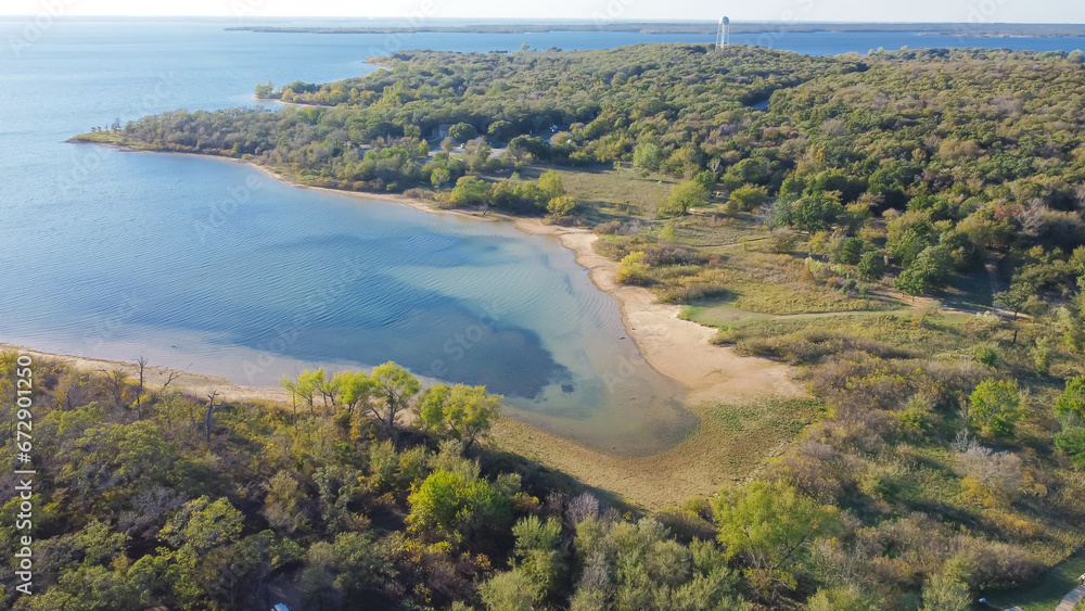 Aerial view a secondary point or hump surrounding by lush green trees and curved sandy shoreline at Isle du Bois Ray Roberts Lake State Park, remote primitive camping sites