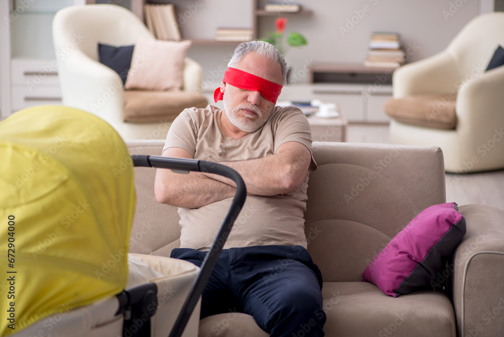 Fototapeta premium Old man looking after newborn at home