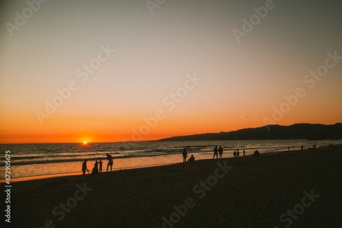 Group of people on the beach at sunset © Wirestock