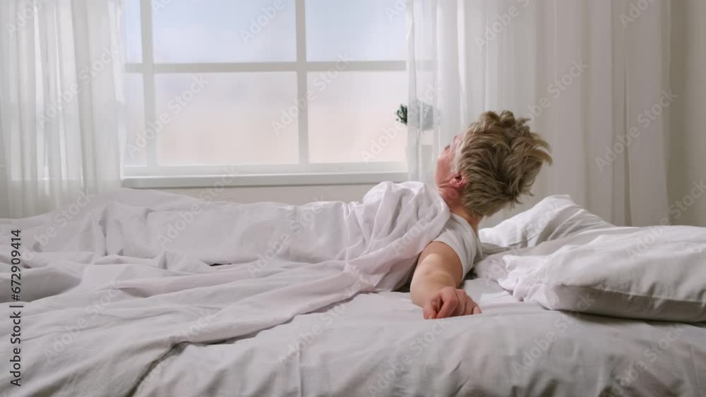 Woman wakes up in morning in good mood after healthy sleep. Middle-aged women sleeping sweetly, waking up, lazily stretching on bed at home, sunlight through window. Concept of beginning of new day. Woman wakes up in morning in good mood after healthy sleep. Middle-aged women sleeping sweetly, waking up, lazily stretching on bed at home, sunlight through window. Concept of beginning of new day.