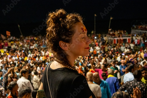 Woman at night in Varanasi watching the Ganga Aarti ritual with many people in Varanasi in India photo