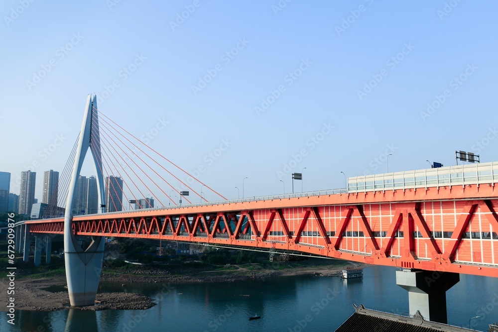 Naklejka premium a red bridge with cars going over it next to a lake