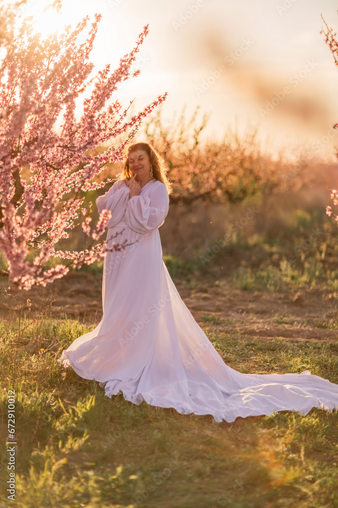Woman blooming peach orchard. Against the backdrop of a picturesque peach orchard, a woman in a long white dress enjoys a peaceful walk in the park, surrounded by the beauty of nature. Woman blooming peach orchard. Against the backdrop of a picturesque peach orchard, a woman in a long white dress enjoys a peaceful walk in the park, surrounded by the beauty of nature.