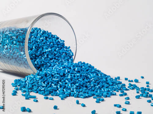 cold cut type blue pearlish masterbatch granules with glass cup in white background photo. This material is a coloring agent for products of the plastics industry