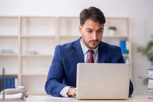 Young male employee sitting at workplace