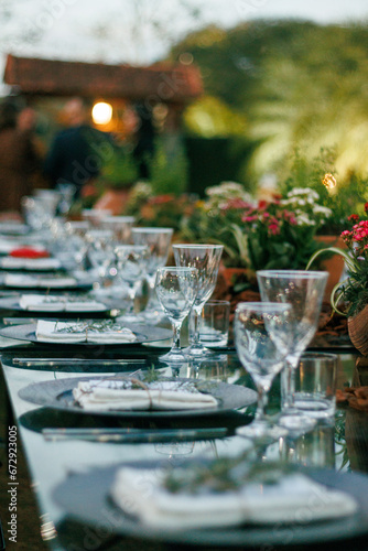 outdoor dining, sophisticated event, crystal glassware, polished plates, rustic centerpiece, wooden decor, potted herbs, table setup, celebration, elegant