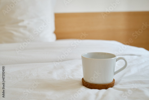 White cup with coffee or tea on the bed. Cozy morning photo. The concept is cozy and warm. Place for text 