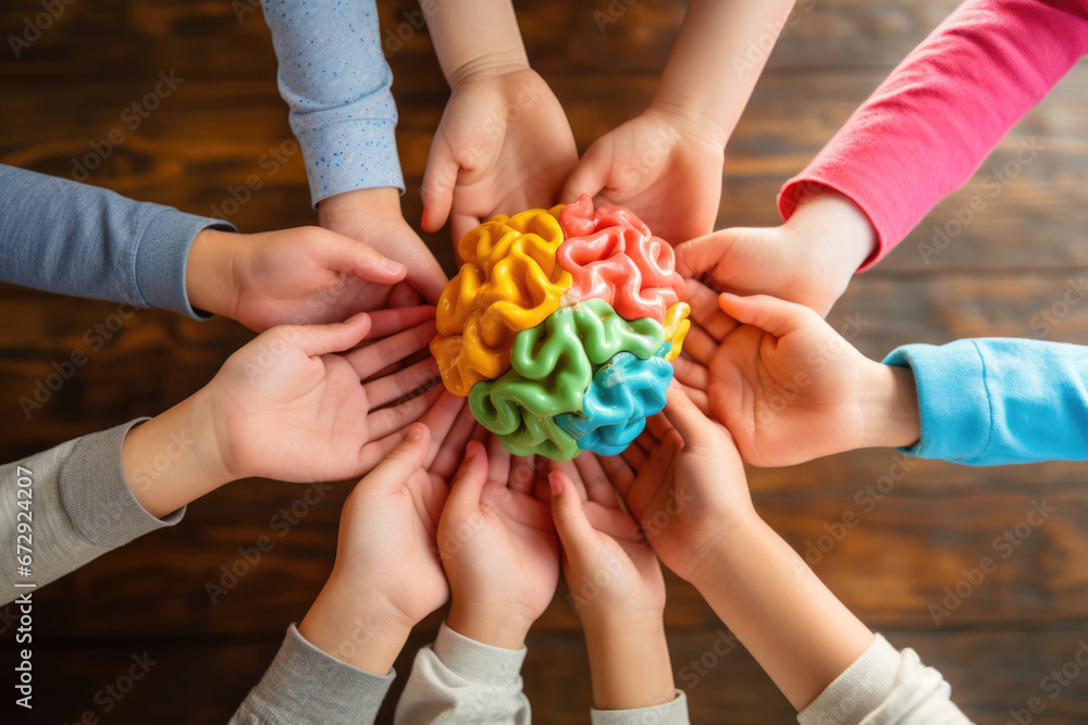 Several children's hands holding a colored brain illustrating Neuro diversity - obrazy, fototapety, plakaty 
