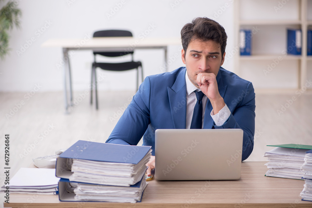 Young male employee and too much work in the office Young male employee and too much work in the office