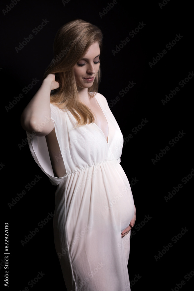 Studio shot of pregnant beautiful young blonde woman posing on black background. Vertically. Studio shot of pregnant beautiful young blonde woman posing on black background. Vertically.