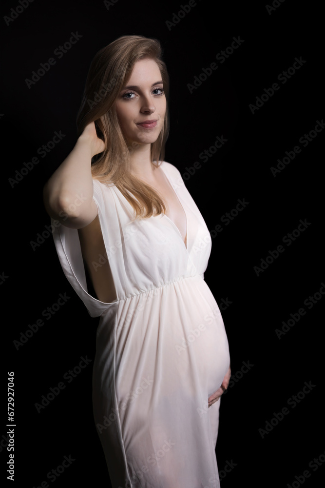 Studio shot of smiling pregnant beautiful young woman posing on black background. Vertically. Studio shot of smiling pregnant beautiful young woman posing on black background. Vertically.