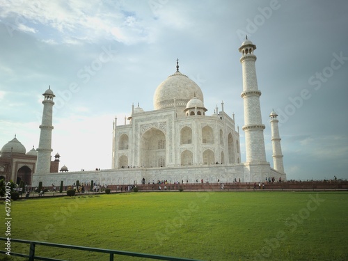 Iconic Taj Mahal in India, with a lush green field and a crowd of people