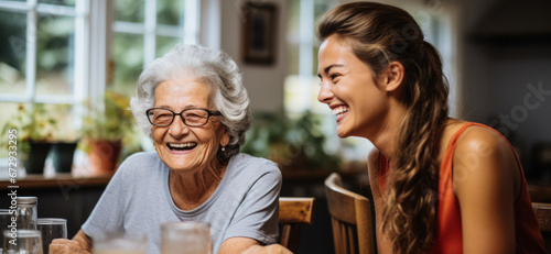 Lighthearted Moments: Young Carer and Elderly Woman Laughing at Kitchen Table photo