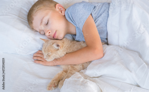 A child in bed cannot fall asleep, yawns, grimaces and plays with a ginger cat.