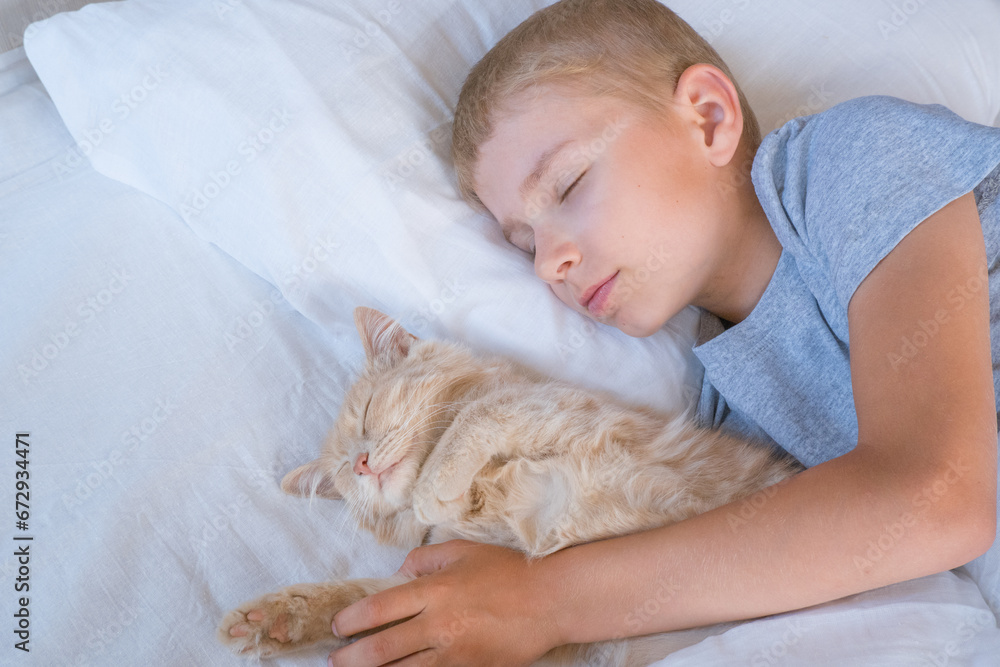 the boy falls asleep and hugs his ginger cat, who sleeps with him under the covers. children and pets. the cat sleeps with the baby. the child is getting ready for bed.