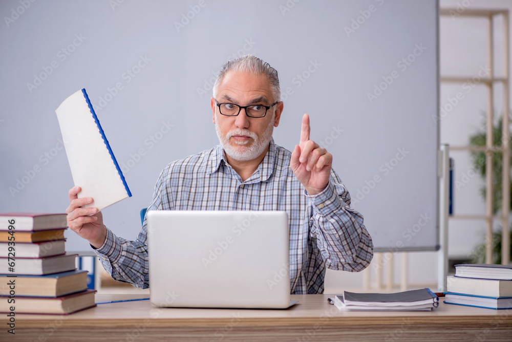 Old male teacher sitting in the classroom Old male teacher sitting in the classroom
